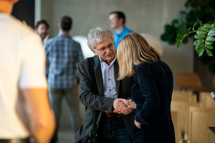 Two attendees greet one another amid a crowd at the event.